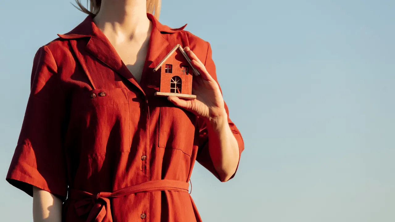 Femme tenant une maison miniature entre les mains